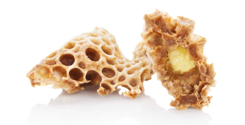 Royal jelly in honeycomb on an isolated white background.