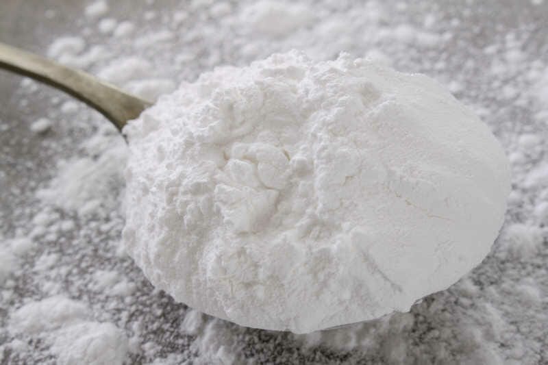 Closeup of a spoon of powdered sugar ready to sprinkle over honey bees.