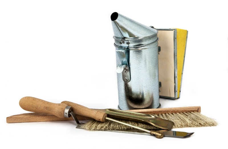 A selection of beekeeper tools on a white background