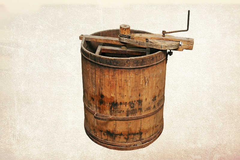 A vintage honey extractor on a plain background